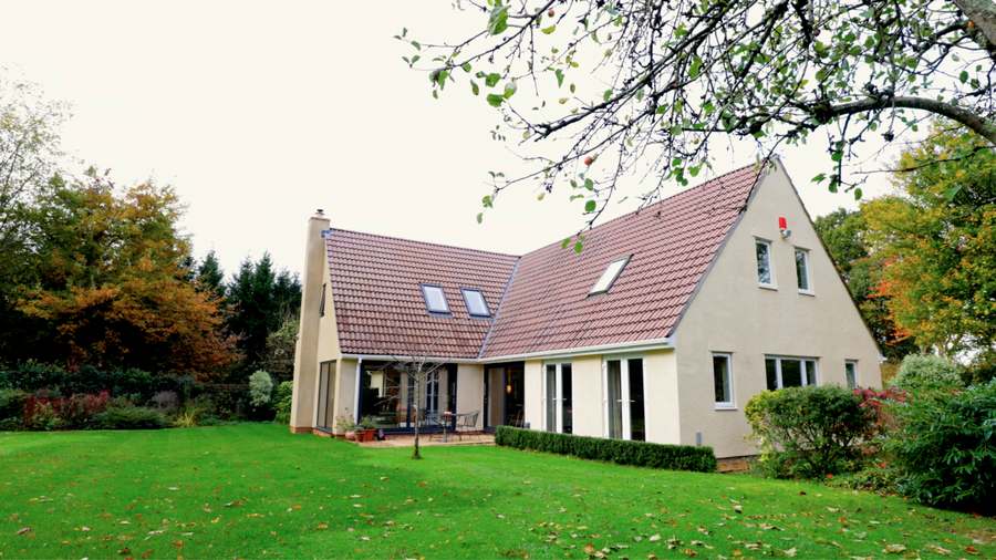 Rendered detached house with a tiled roof, seen across the rear lawn